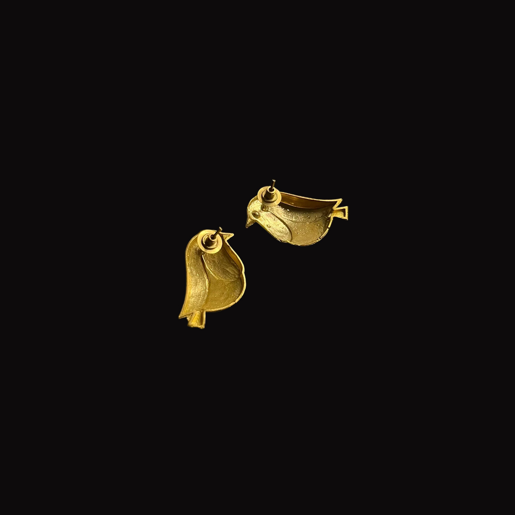 Pair of gold bird-shaped earrings on a black background