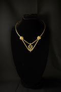 Gold necklace on a black stand against a black background