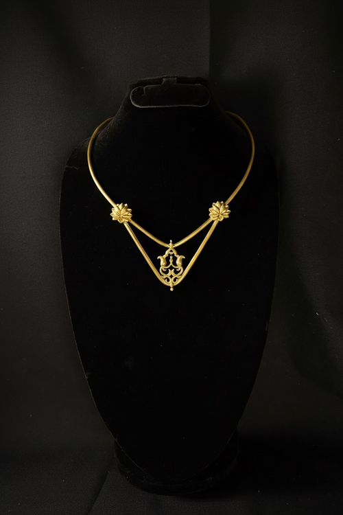 Gold necklace on a black stand against a black background