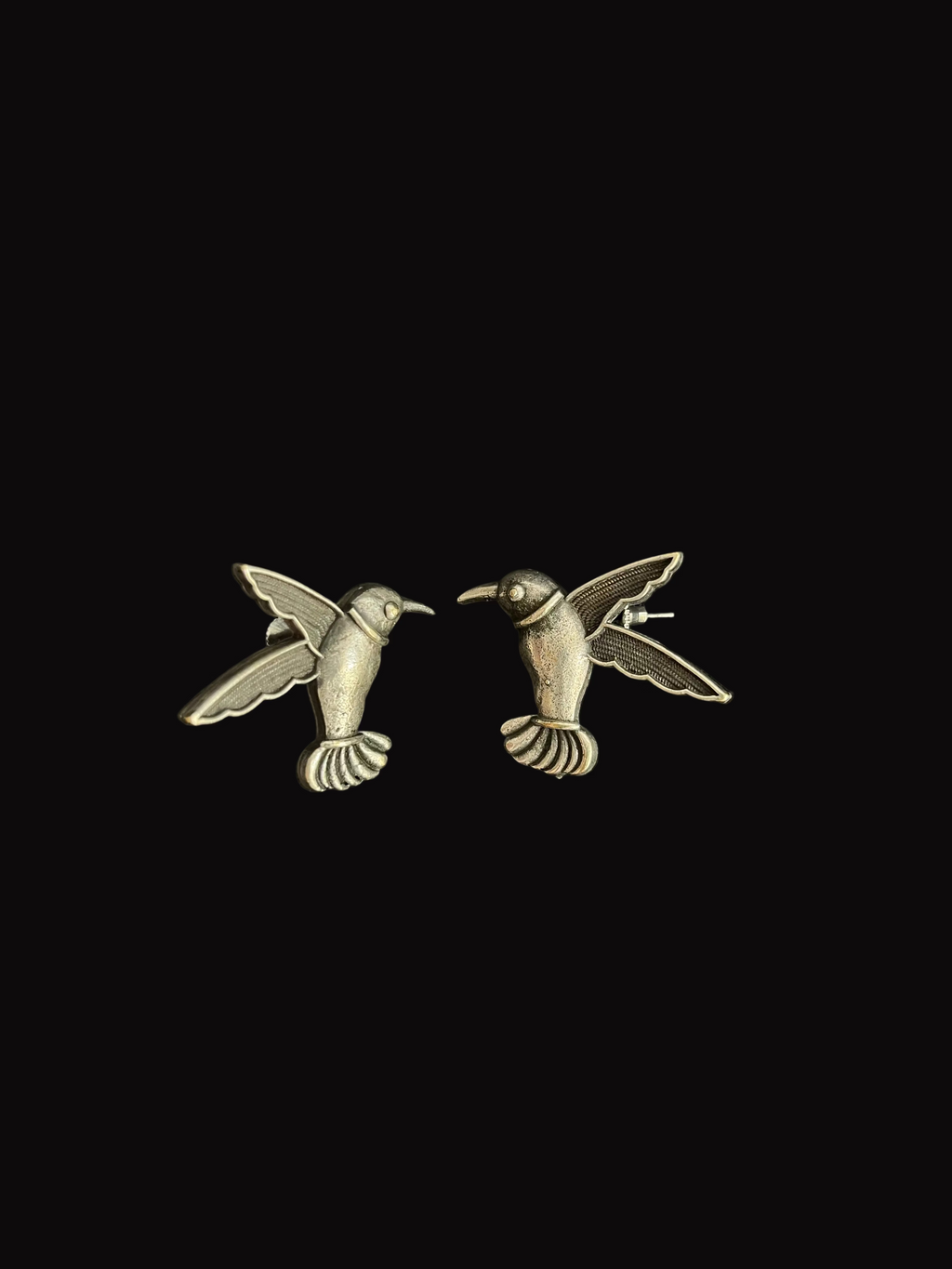 Pair of silver hummingbird earrings on a black background
